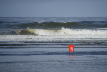 Orange bucket in front of waves