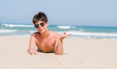 Young child on holidays at the beach very happy pointing with hand and finger to the side