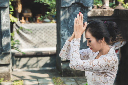 balinese woman praying at temple on small shrines in houses