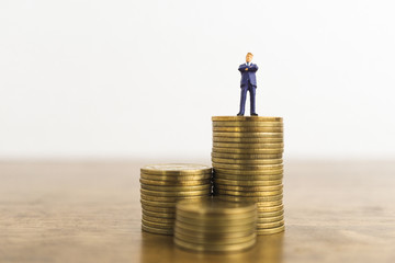 business growth high level concept. a little figure miniature businessman stand on stacks of high coins.