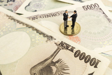 businessman handshake concept. a little figure miniature businessman partners concluding deal and stand on coins.