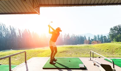 Poster Young woman practices her golf swing on driving range, view from behind © tonjung