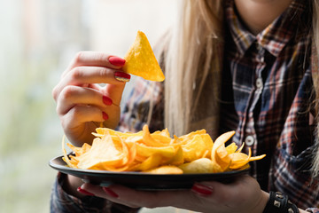 unhealthy fast food snacks. bad nutrition habits. woman eating crispy delicious nacho chips