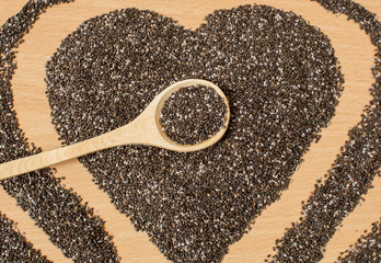Healthy Chia seeds in the form of a heart. Chia in a wooden spoon on a wooden table close-up.