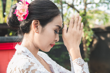 balinese woman praying at temple on small shrines in houses