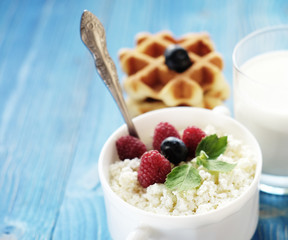 Cottage cheese with berries, waffles and milk on a wooden