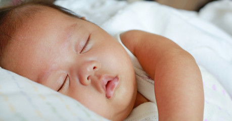 Close up infant baby boy sleeping on the bed.