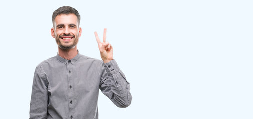 Young hipster man showing and pointing up with fingers number two while smiling confident and happy.