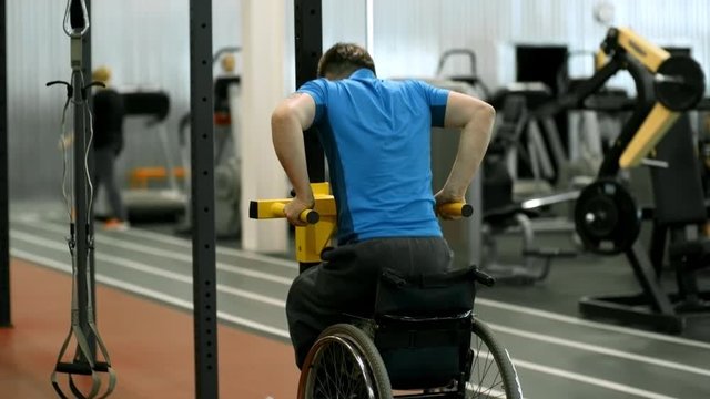 Tilt up with rear view of paraplegic man in wheelchair doing dips exercise