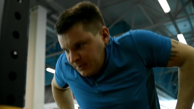 Tilt up of determined paraplegic man in wheelchair doing dips exercise and breathing hard while training in gym