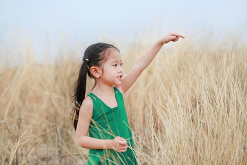 Cute little child girl pointing up in summer field outdoor. Freedom style.