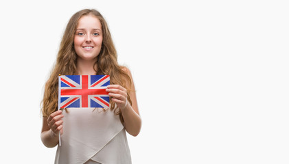 Young blonde woman holding flag of UK with a happy face standing and smiling with a confident smile showing teeth