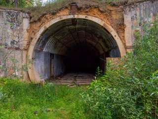 Old abandoned undetected military undeground tunnel storage among wild tall weeds. Kaluzhskaya...