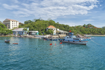 Fototapeta na wymiar southern port area, ship and boat parking in a bay, buildings, coastline, amidst tropical greenery, blue sky and Nha Trang clouds, Vietnam