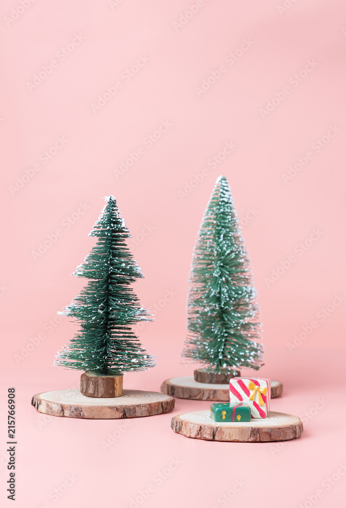 Poster christmas tree on wood log slice with present box on pastel pink studio background.holiday festive c