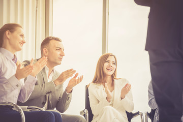 business people sit in a row smiling and clapping in business training