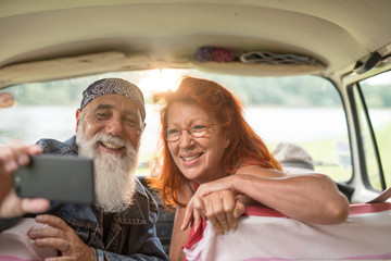  old hipster couple sitting in a car doing a selfie with a phone