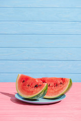 close up view of juicy watermelon slices on plate on blue backdrop