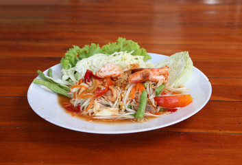 papaya salad with shrimp and vegetables, cabbage and yardlong bean in white dish on the wooden table.