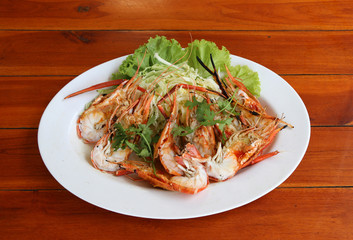 Grilled shrimp and cut in half with vegetables and cabbage  in white dish on the wooden table.