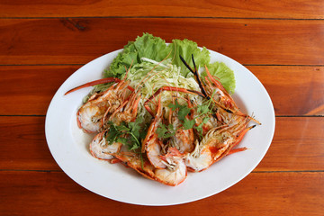 Grilled shrimp and cut in half with vegetables and cabbage  in white dish on the wooden table.