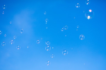 Soap bubbles in flight against the blue sky