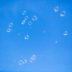 Soap bubbles in flight against the blue sky