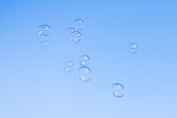 Soap bubbles in flight against the blue sky