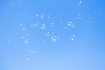 Soap bubbles in flight against the blue sky