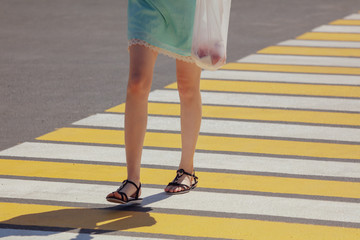 Legs of a girl crossing the road through a zebra
