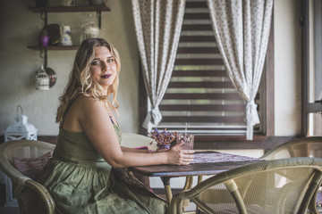 American beautiful young plus size female with white hair wearing green dress sitting comfortably on kitchen with Provence interior