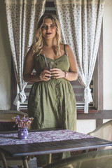 American beautiful young plus size female with white hair wearing green dress sitting comfortably on kitchen with Provence interior