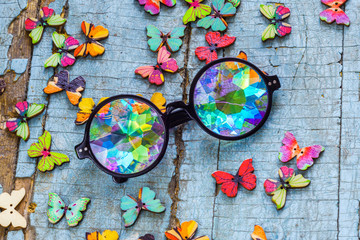 designer kaleidoscope glasses on a blue wooden background with butterflies
