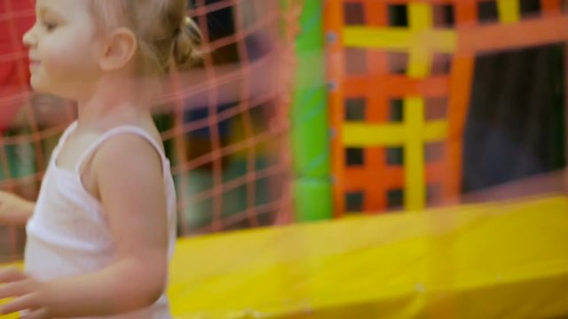 Little girl jumps on a bright multi-colored indoor trampoline