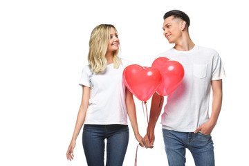 couple standing with bundle of heart shaped balloons and looking at each other isolated on white