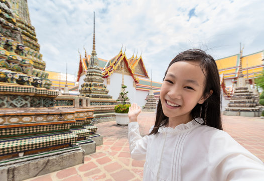 Cute happy smiling tourist girl taking self-portrait picture  at Wat Phra Chetuphon or Wat Pho is a Buddhist temple in the city of Bangkok,Thailand, summer vacation,travel concept.