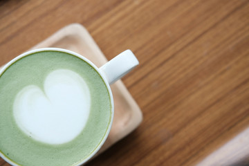 hot matcha green tea with heart latte art on wood table