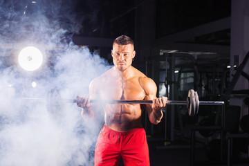 Fototapeta na wymiar Muscular young man lifting weights in gym
