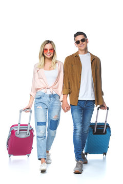 Young Happy Couple Holding Hands And Walking With Suitcases Isolated On White