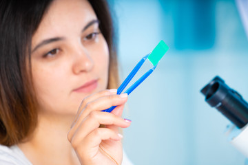 technician girl with microfluidic device LOC in microbiological lab