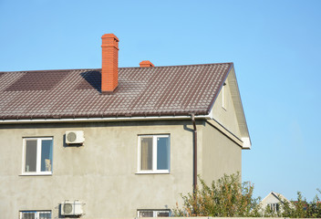 House with metal roof, brick chimney, rain gutter and insulate plaster, stucco walls outdoors.