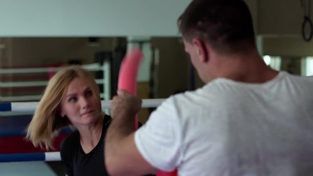 Young woman training at boxing ring with coach