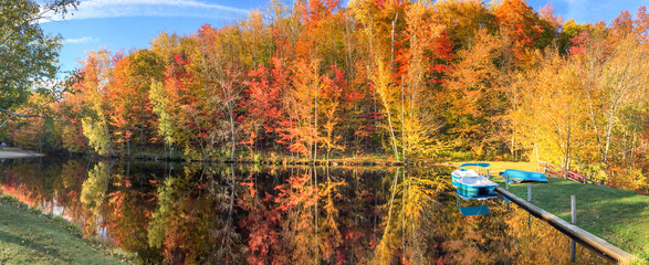 Lake, boat and trees in foliage season, panoramic view