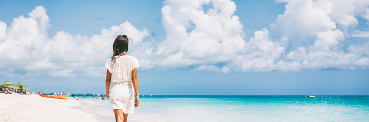 Luxury beach vacation travel woman relaxing on paradise tropical holiday destination for sun getaway. Girl wearing beach dress walking panoramic banner. - obrazy, fototapety, plakaty