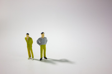 Two miniature businessman on gray background.