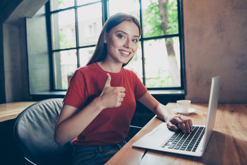 Portrait of beautiful, attractive girl freelancer showing thumbs up working remotely in cafe behind...