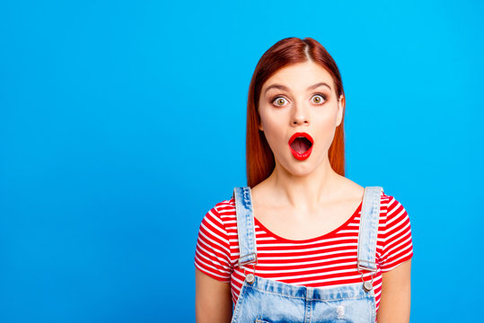 Nice red straight-haired vivid young shocked girl showing with opened mouth, wearing casual, isolated over blue background, copy space