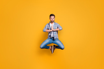 Full-body portrait of levitates in the air meditating and concentrating isolated on shine yellow background