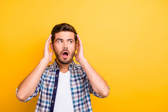 Portrait of young brunet looking aside opened mouth and rise hands up isolated on isolated on bright yellow background with copy space for text