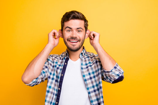 Portrait of attractive funny man stretching ears imitating monkey and looking at camera isolated on vivid yellow background
